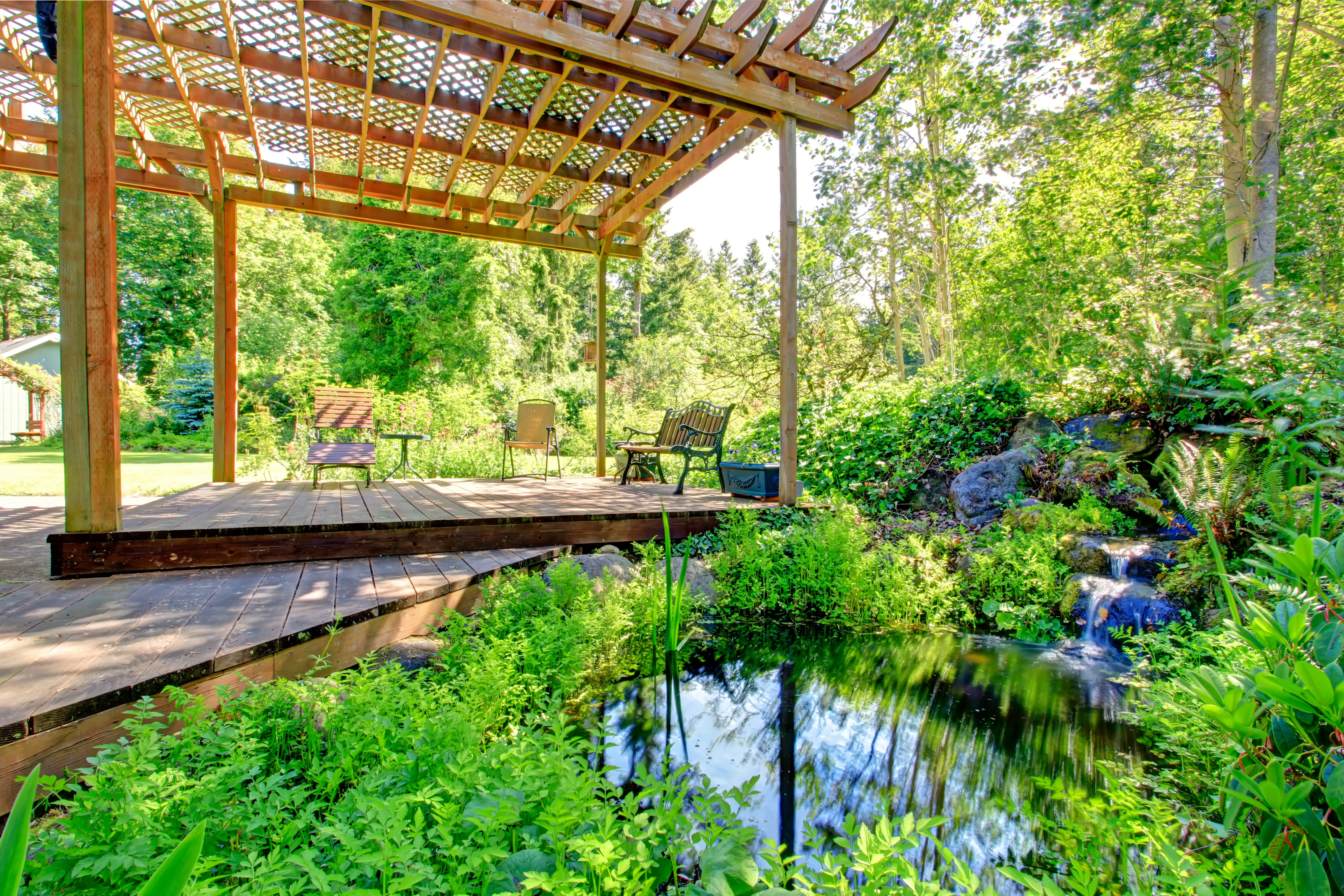 Illuminated blue lanterns hang under a pergola at dusk, creating a warm, inviting ambiance.